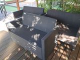a black wicker couch sitting on a wooden deck