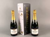 deux bouteilles de champagne posées à côté d'un carton de vin sur une table