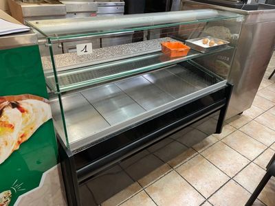 a glass display case with pizzas on it in a restaurant