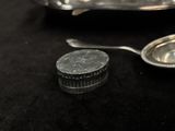 a silver spoon and a coin on a black table