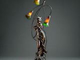 a bronze statue of a woman holding a lamp