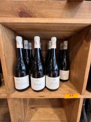Plusieurs bouteilles de vin sont posées sur une étagère en bois dans un caviste.