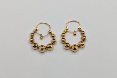 une paire de boucles d'oreilles en or sur fond blanc