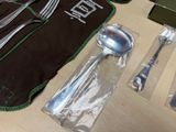 a lot of silverware on a table with a black cloth