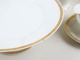 a white plate with a gold trim and a white cup and saucer