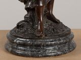 bronze statue of a woman sitting on a rock with a bird in her hand