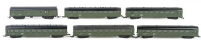 six green train cars are lined up on a white surface