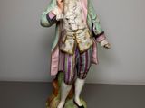 a figurine of a man with a pink coat and purple pants
