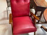 a red chair sitting in a room with a table and chairs