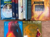 plusieurs livres posés sur une table en bois, avec une femme en robe rouge devant eux