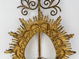 a gold sunburst hanging on a wall next to a white wall
