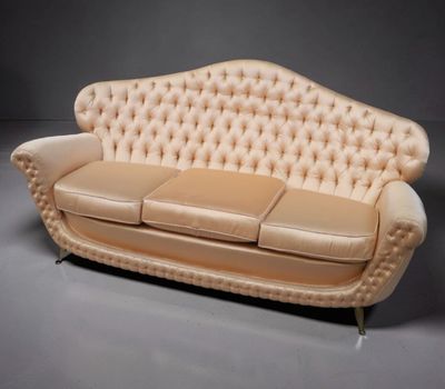une photo d'un canapé en cuir beige, avec un dossier et des accoudoirs capitonnés
