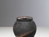 a black vase sitting on a table with a white background