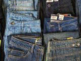a lot of jeans that are stacked on top of each other