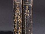 two old books sitting on top of each other on a table