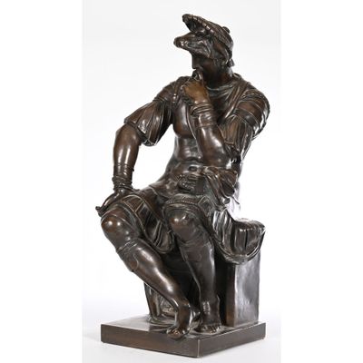 a statue of a man sitting on top of a wooden block