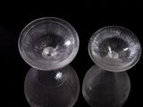 two clear glass bowls sitting on top of a black surface