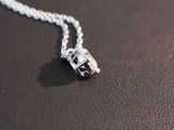 a silver necklace with a crystal on it on a black surface