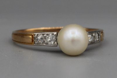 un gros plan d'une bague en perle et diamant posée sur une table