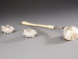 three pieces of silver on a table with a spoon and spoon rest
