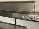 a large metal counter in a kitchen with a microwave on top of it