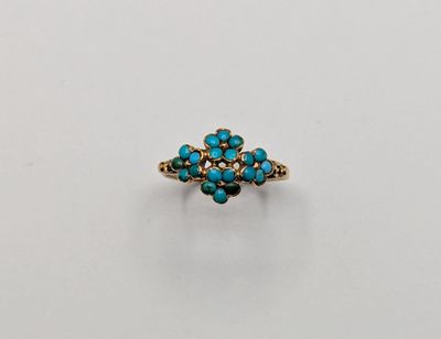 une bague en or sertie d'une pierre turquoise sur un fond blanc