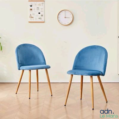 une paire de chaises bleues dans une pièce où est accrochée une horloge au mur