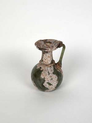 une image représentant un vase vert et blanc posé sur une surface blanche
