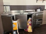une cuisine équipée d'un plan de travail en inox et d'une poubelle