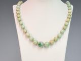 a close up of a necklace on a mannequin with green beads