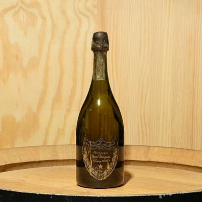 a bottle of wine sitting on top of a wooden barrel