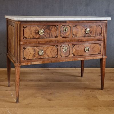 une commode au plateau en marbre posée sur une table en bois