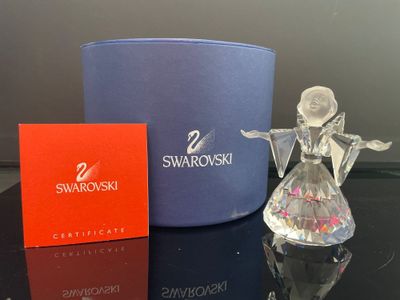 une figurine d'ange en verre posée à côté d'une boîte de Swarovski