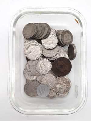 un récipient en verre rempli de pièces de monnaie posé sur une surface blanche