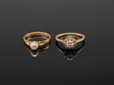 two gold rings with pearls and diamonds on a black surface