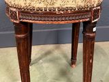 un tabouret ancien en bois avec une assise rembourrée à motifs floraux