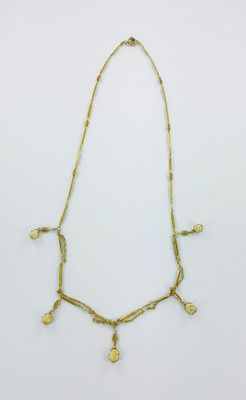 un collier en or orné de pièces de monnaie sur fond blanc