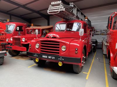 three red fire trucks are parked in a garage with a ladder