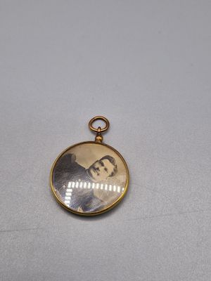un cadenas doré sur lequel figure la photo d'un homme en costume-cravate