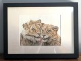 painting of a couple of lions in a black frame on a wooden table