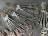 a lot of silver forks and spoons that are on a table