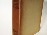 an old book sitting on top of a white table next to a white wall