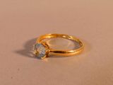 une bague en or sertie d'un diamant, posée sur une table