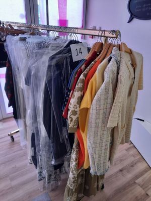 des vêtements suspendus à un portant dans un magasin de vêtements, près d'une vitrine