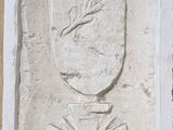 une plaque apposée sur le mur d'un immeuble, sur laquelle figure un vase