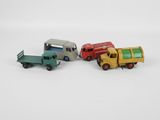 quatre camions miniatures posés les uns à côté des autres sur une surface blanche