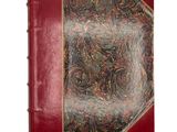 an old book with a red cover sitting on top of a white surface