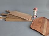 three wooden cutting boards and a small figurine on a table