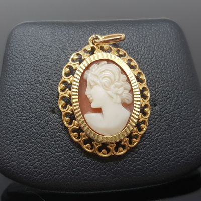 un gros plan sur un pendentif plaqué or représentant le visage d'une femme