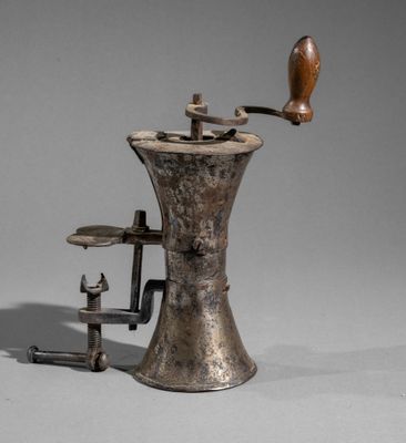 an old coffee grinder with a wooden handle on a gray surface